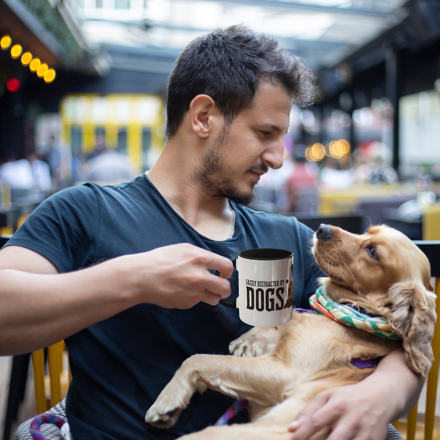  A man sits with a warm smile, cradling his Golden Retriever in one arm, while the other hand grips a Dogs Pure Love mug, displaying the text 'Easily distracted by dogs.'