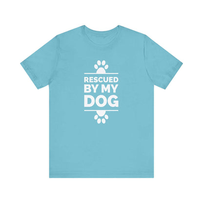  Against a white backdrop, a Dogs Pure Love Turquoise unisex tee showcases paw prints and the heartwarming message 'Rescued by my Dog.'