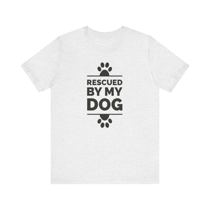 On a clean white background, a Dogs Pure Love ash color unisex tee exhibits adorable paw prints and the heartfelt expression 'Rescued by my Dog.'