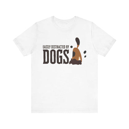 On a white surface, a Dogs Pure Love white unisex t-shirt features a playful slogan ‘Easily Distracted by Dogs,’ and a graphic of a dog digging.