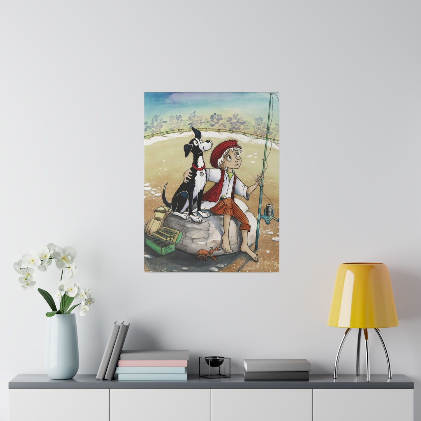 A 24" x 32" 'Dogs Pure Love Fishing' canvas hangs on a wall, above a narrow cabinet, which features a yellow lamp, books, and a vase of flowers.