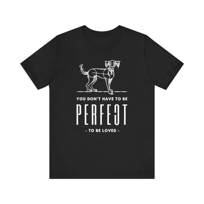  The Dogs Pure Love black unisex tee prominently presents the slogan 'You don't have to be perfect to be loved,' against a white background.