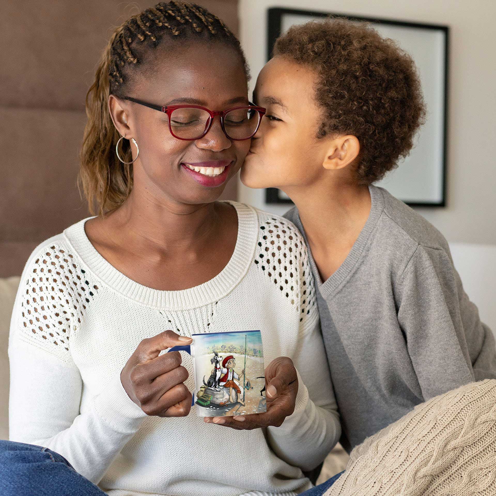 A young boy kisses his mother who sits holding a Dogs Pure Love ceramic mug.