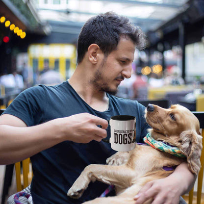 A man lovingly cradles his Golden Retriever with one arm while raising his ‘Dogs Pure Love, Dog Dig’ mug with the other, in a busy indoor area.