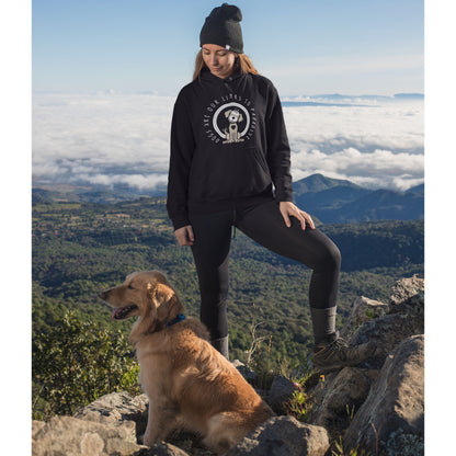  A woman, clad in a 'Dogs are Paradise' hoodie, stands atop a rocky mountain with her Golden Retriever, overlooking a scenic backdrop of trees and clouds.