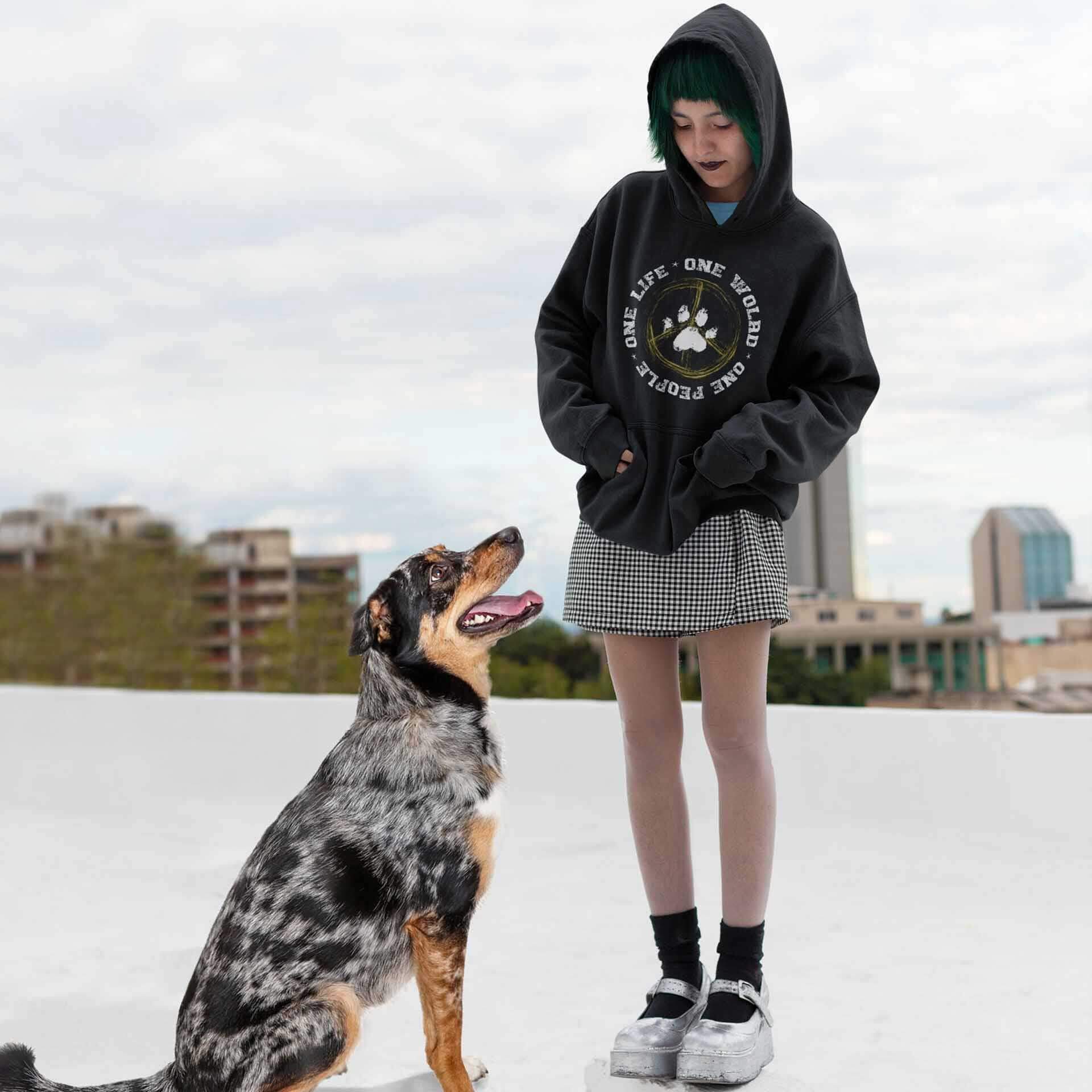  A young woman, donning a 'Dogs Pure Love, One World' hoodie, gazes affectionately at her dog in a city center.