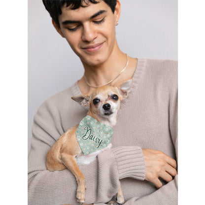  A man holds a Chihuahua wearing a bandana with the name 'Daisy' written on it.