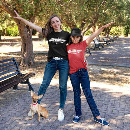  A mother and daughter stand on a boulevard, pointing upwards, dressed in Dogs Pure Love Supermum and Superkid tees, with their Chihuahua standing in front.