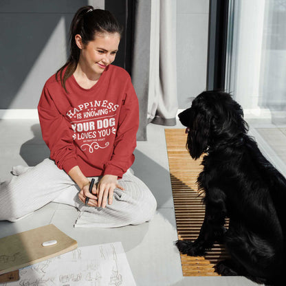 A woman, clad in a 'Dogs Pure Love' red sweatshirt, sits on the floor drawing, accompanied by her Cocker Spaniel.