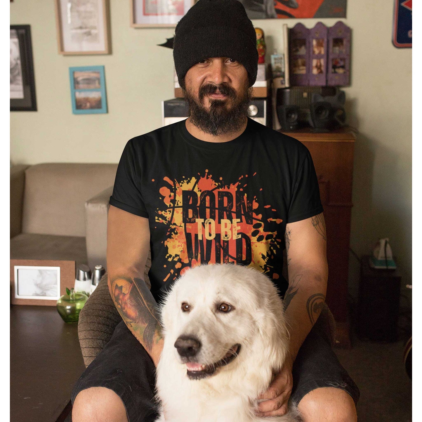 A man wearing 'Dogs Pure Love, Born to be Wild' unisex tee sits on a lounge chair with his white Eskimo dog in front.