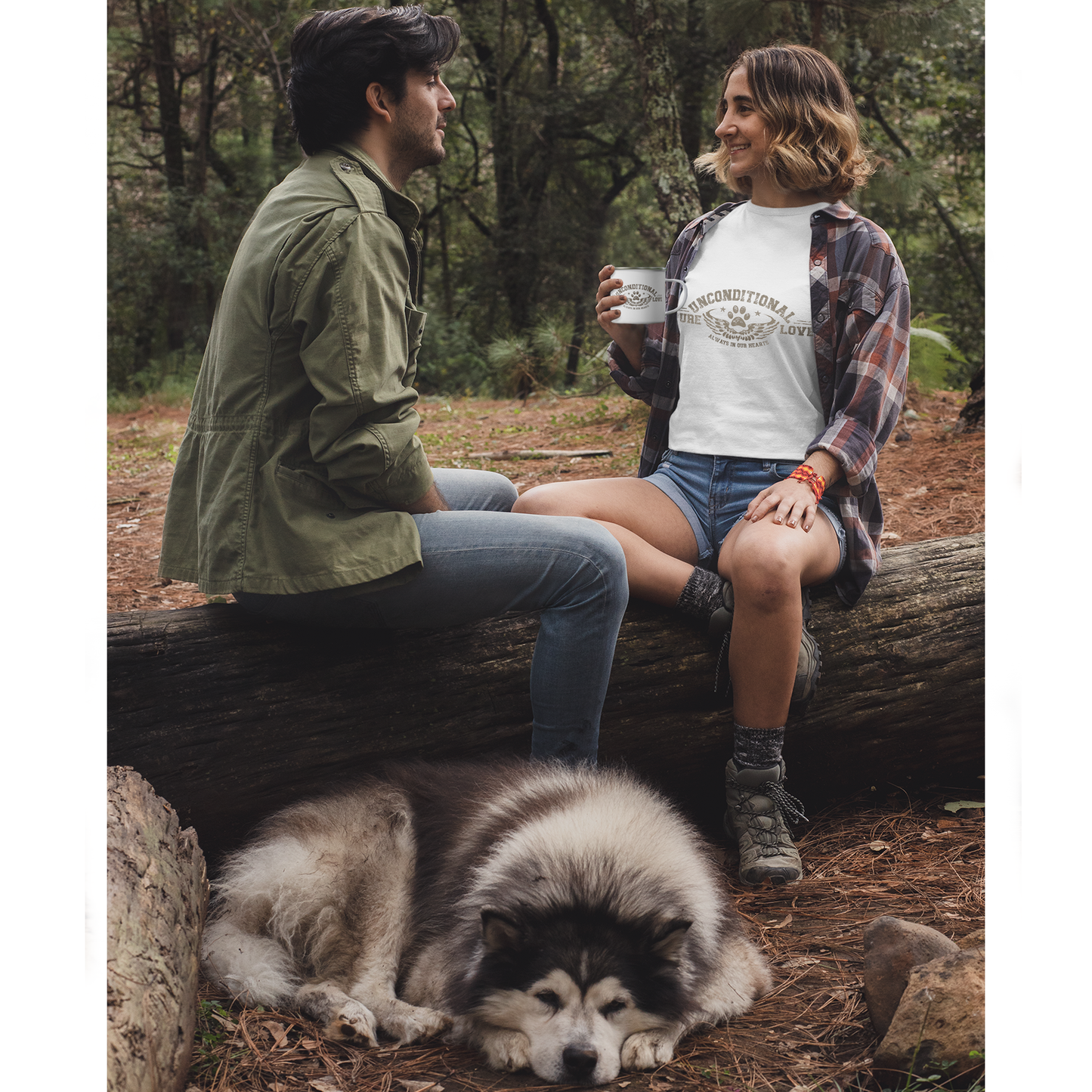  In a forest setting, a couple sits on a log with their Husky lying beside them. The woman holds her enamel Dogs Pure Love mug, while wearing a tee adorned with the same slogan: 'Unconditional Pure Love, always and forever.'