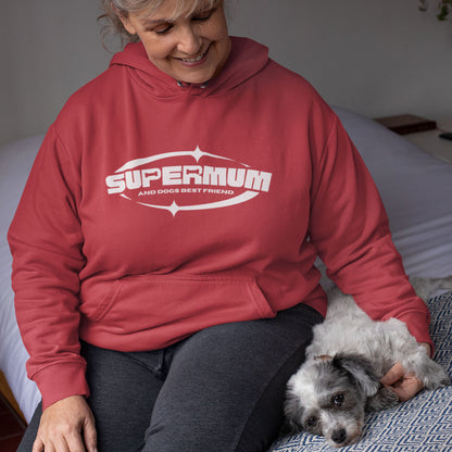 A woman wears a red 'Supermum' print by Dogs Pure Love as she sits on the bed cuddling her dog. 