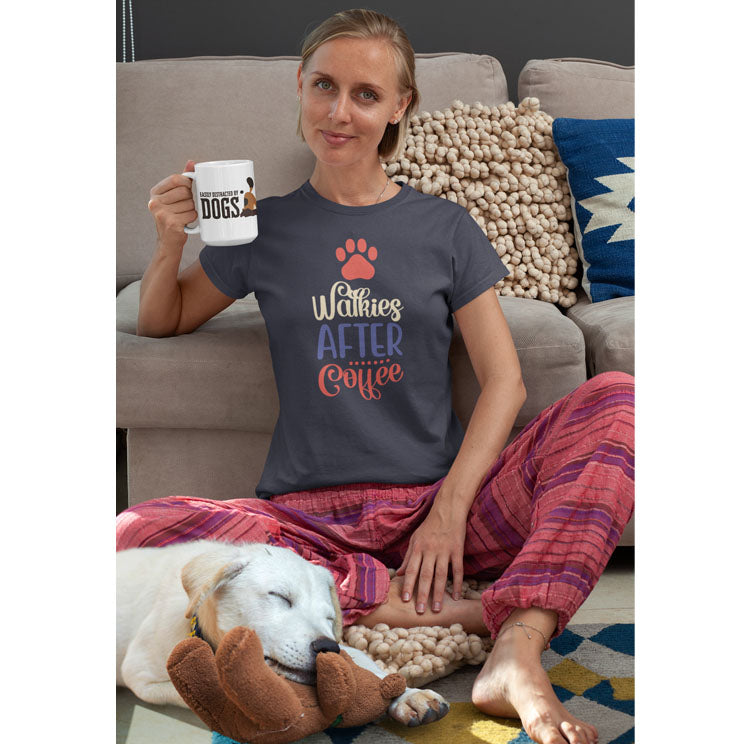  Wearing pajama bottoms and a 'Dogs Pure Love, Walkies After Coffee' tee, a woman sits on the floor with a mug, as her Golden Retriever cuddles a teddy bear beside her.